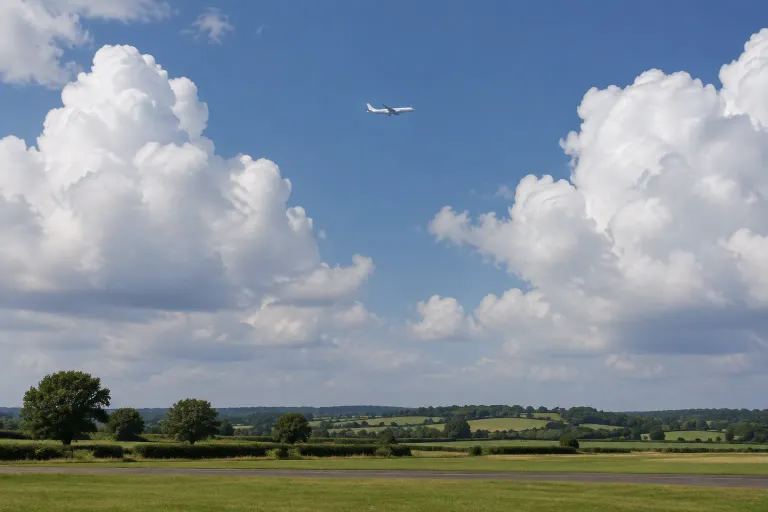 An airliner climbing between tall cumulus clouds above green fields