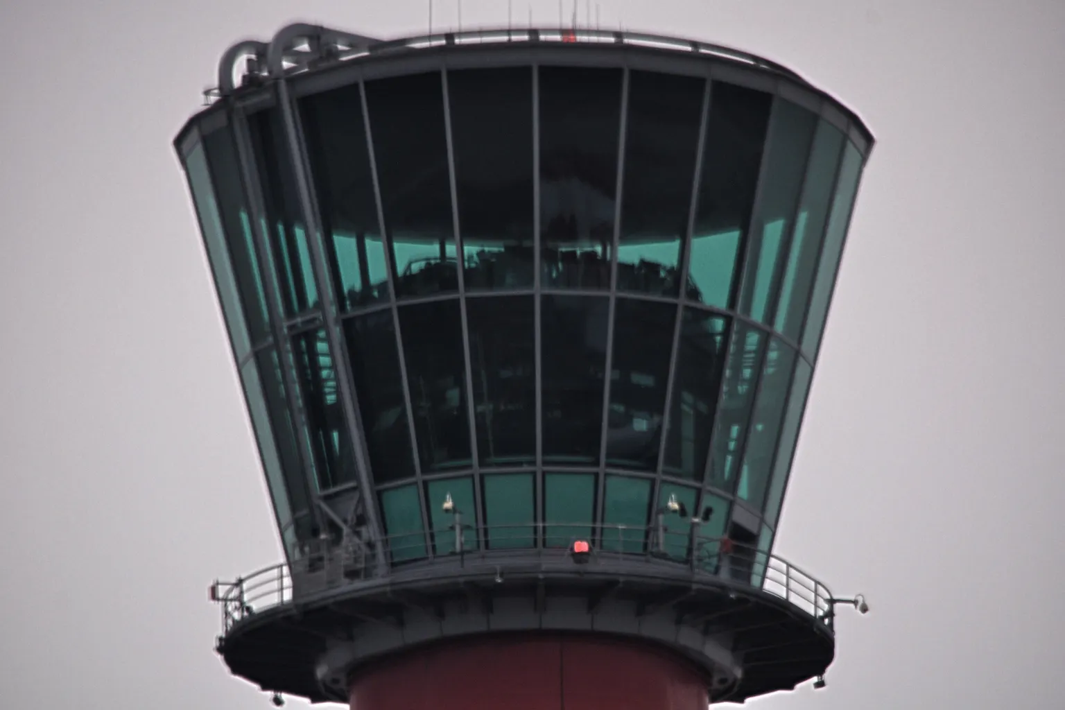 The glass cab of the air traffic control tower at Heathrow, against a pale sky.