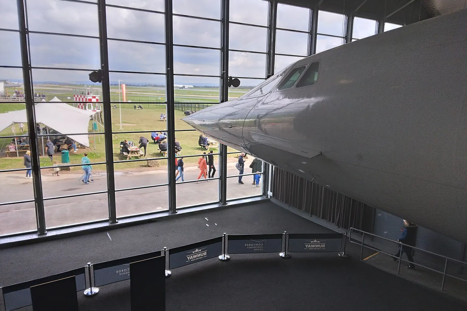 Inside the Concorde hangar at Manchester Airport Runway Visitor Park: the nose of Concorde beside tall windows onto the park.
