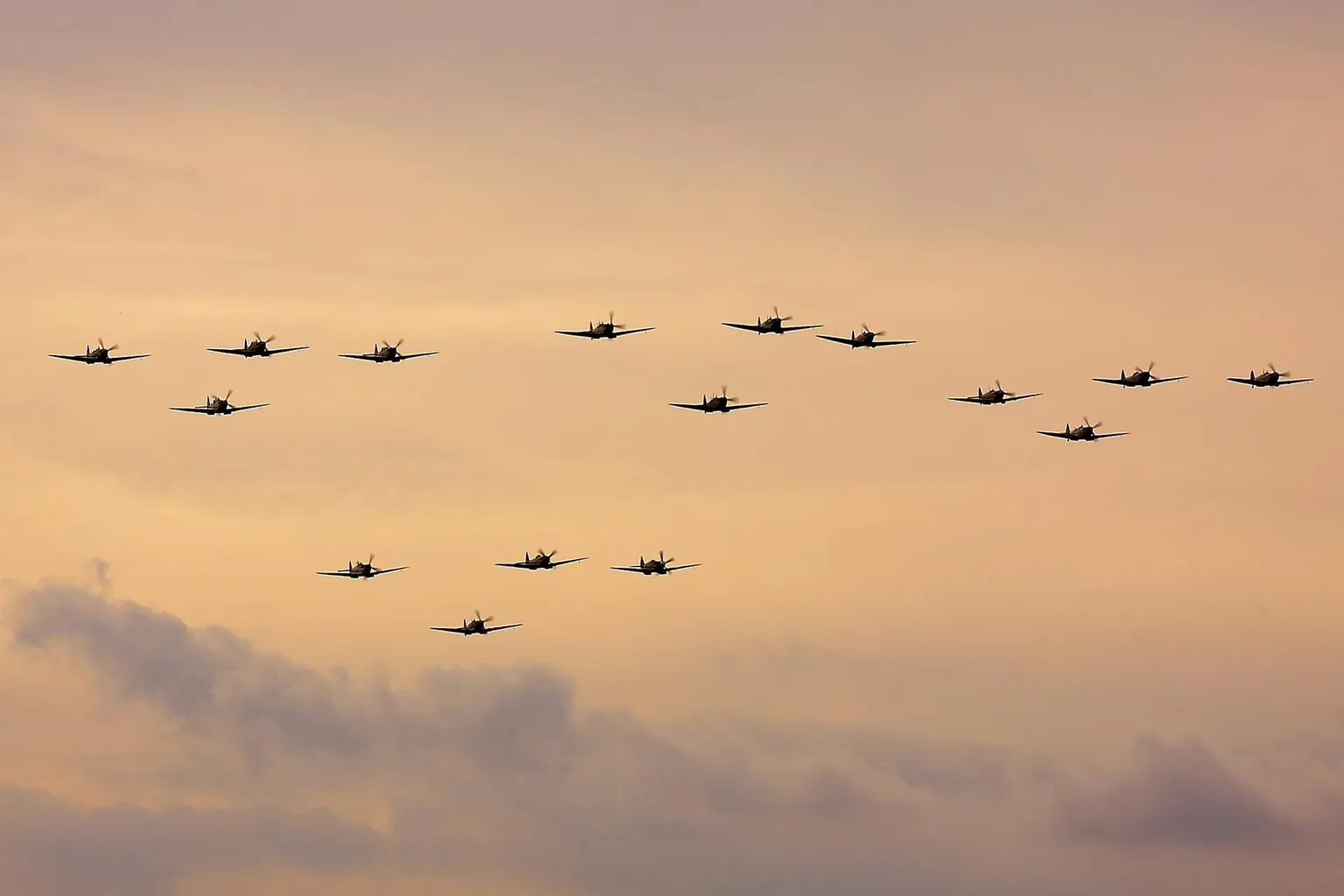 A formation of Spitfires flying against an evening sky at Duxford.
