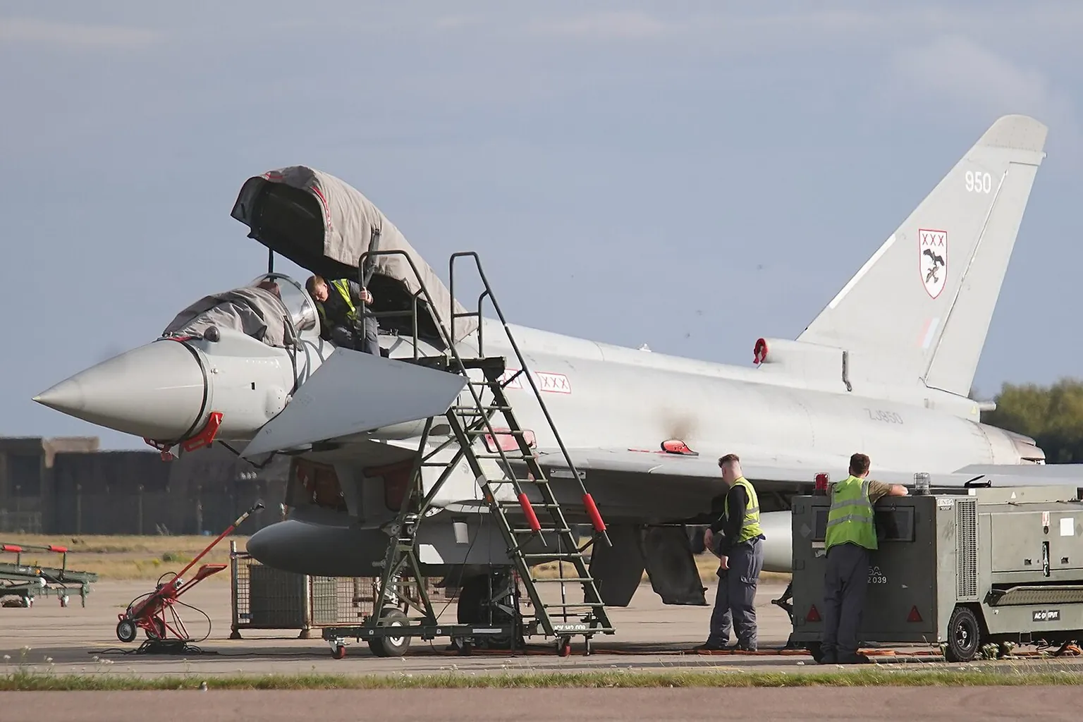 RAF Typhoon ZJ950 on the ground at RAF Coningsby, canopy open, ground crew in hi-vis beside a power unit.