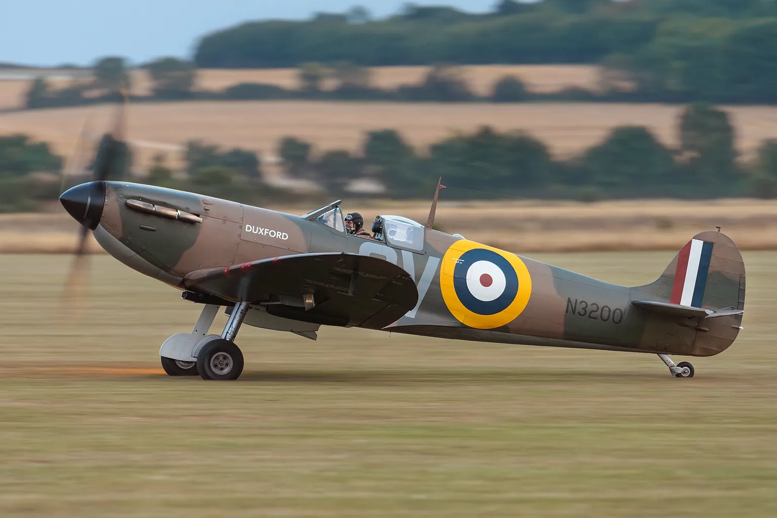 Spitfire Ia N3200 in Battle of Britain markings taking off from the grass at Duxford, 2024.