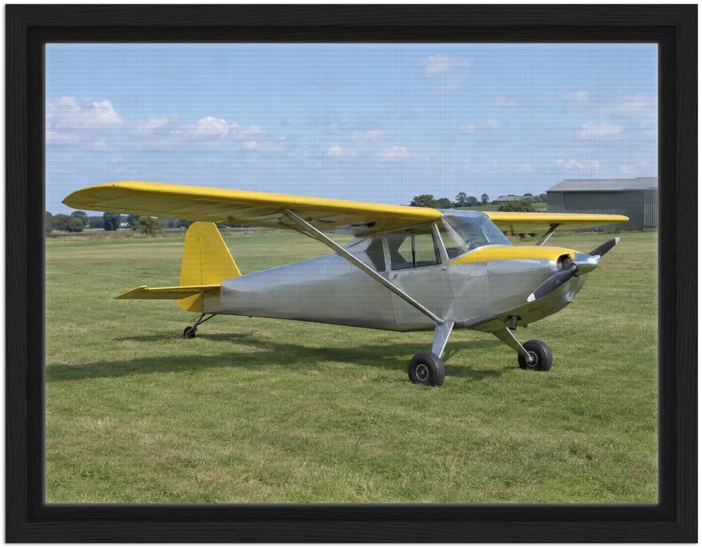 Example render of a canvas in a black frame: a silver and yellow light aircraft parked on grass