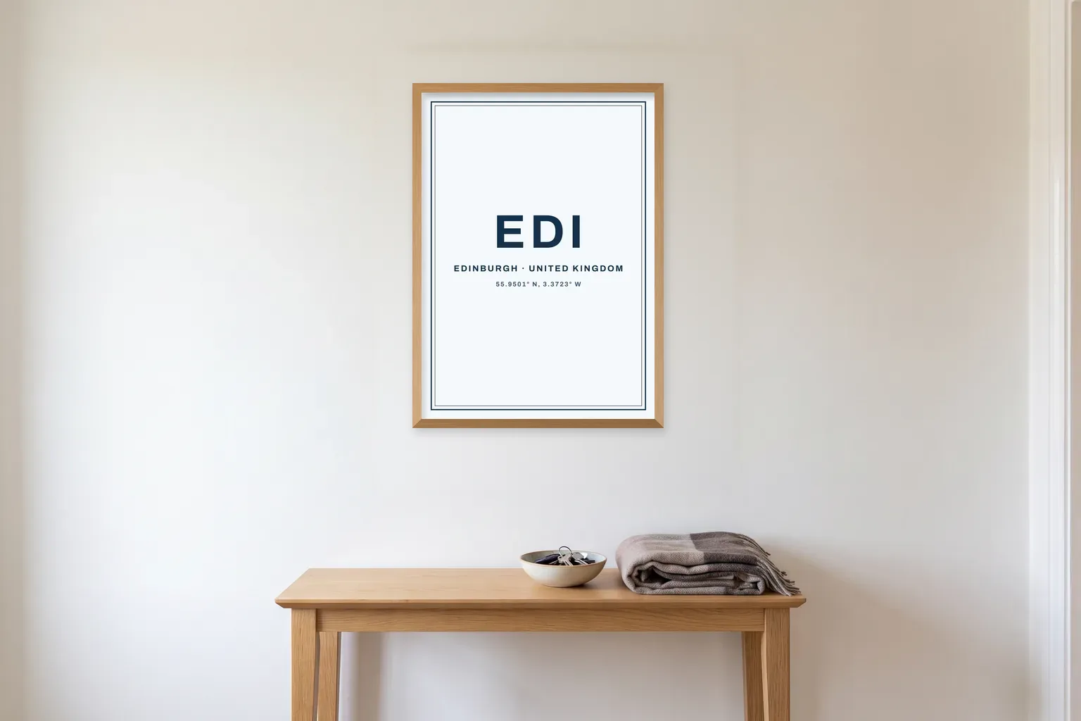 Illustrated mockup: an EDI airport code print for Edinburgh in a slim natural wood frame above a hallway console table.